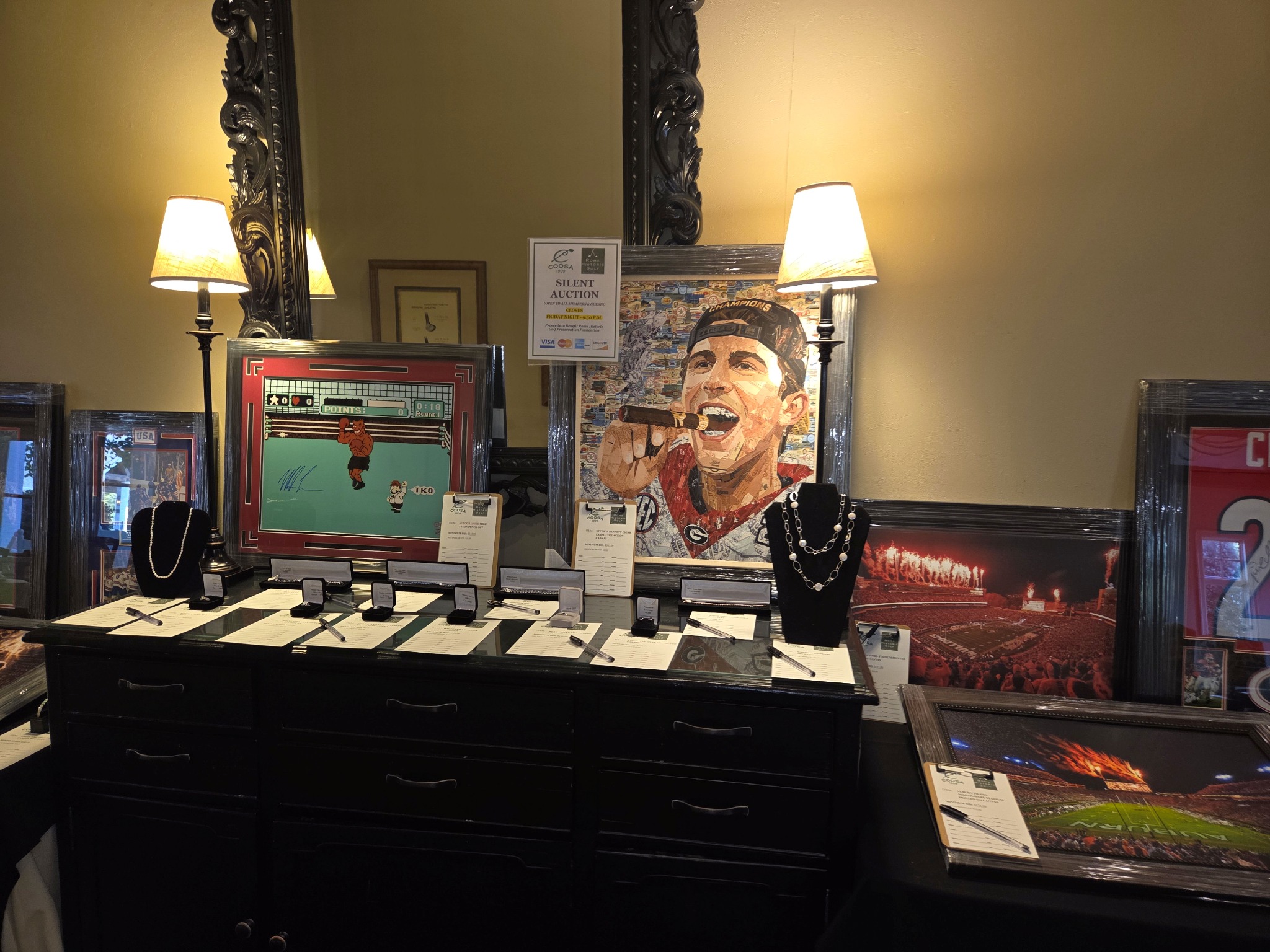 Necklaces on black display stands and jewelry boxes alongside sports memorabilia at a Heritage Sports Gallery silent auction